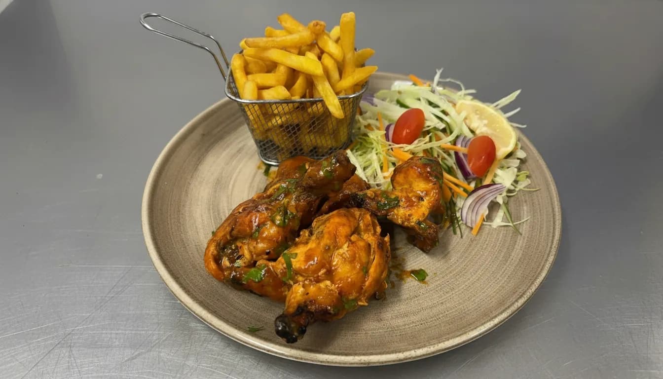 Peri peri chicken with fries, dressed leaves, and lemon wedges.