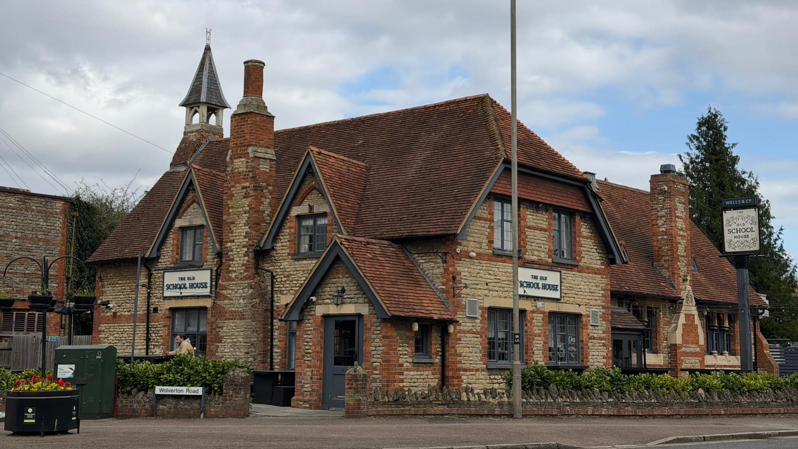 Front-garden view of The Old School House showing outdoor benches and the brick pub exterior.