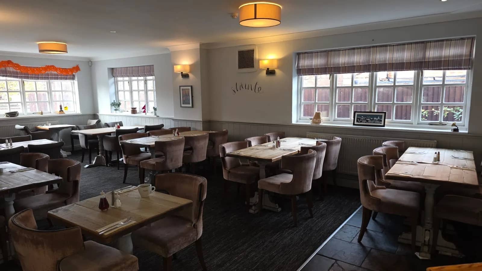 Dining area with tufted seating, chalkboard menu, and framed art at The Prince of Wales.
