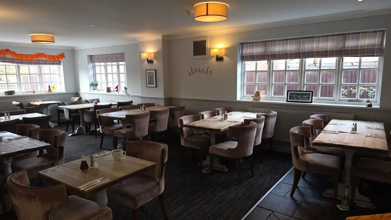 Dining area with tufted seating, chalkboard menu, and framed art at The Prince of Wales.