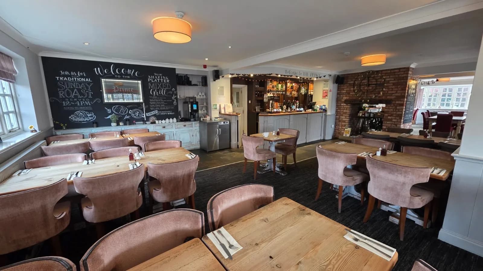 Main restaurant view with banquettes, timber beams, and pendant lights at The Prince of Wales.