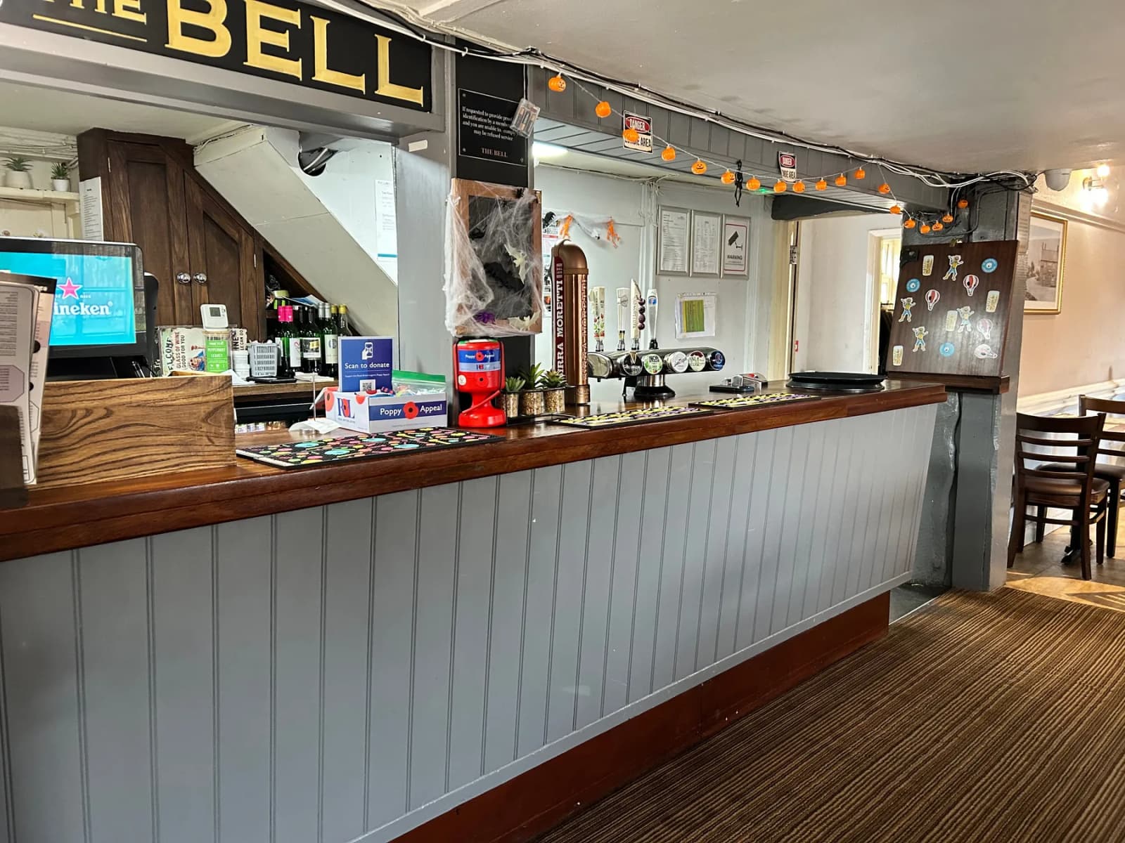 Close-up of The Bell bar counter with brass beer taps and hanging glassware.