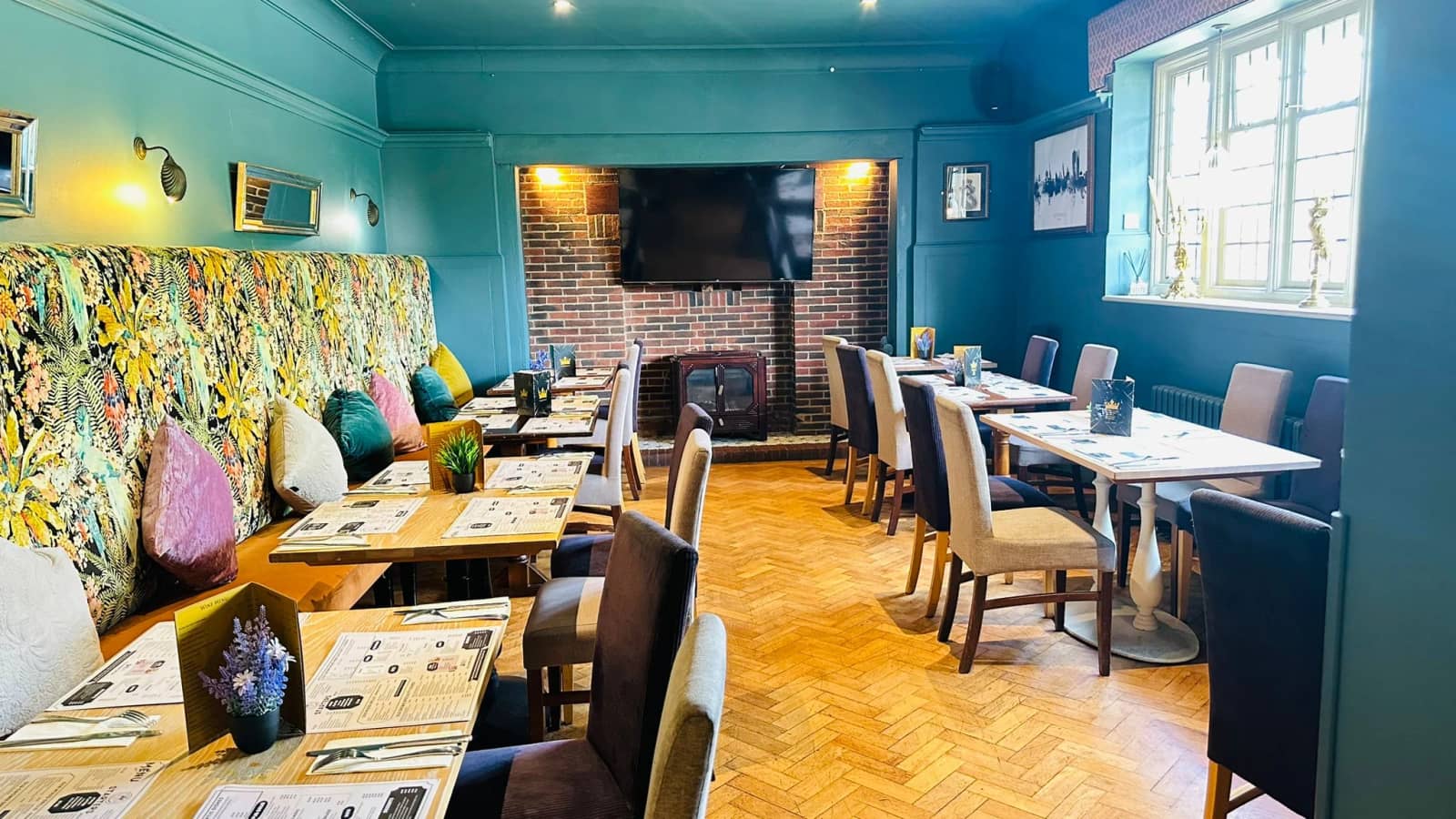 Art Deco dining room at The Old Crown with velvet banquettes and set tables.