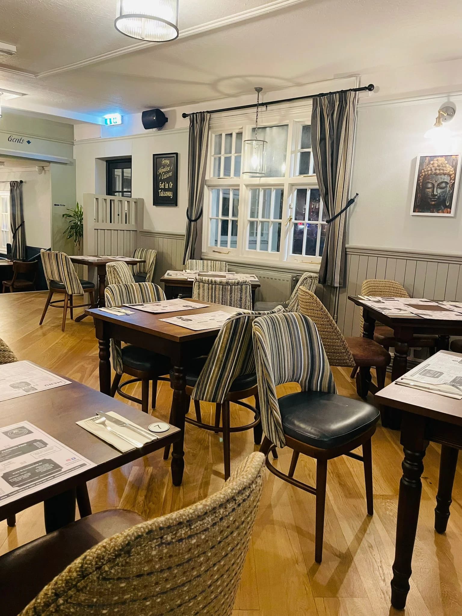Sunlit dining space with striped chairs and bay windows.