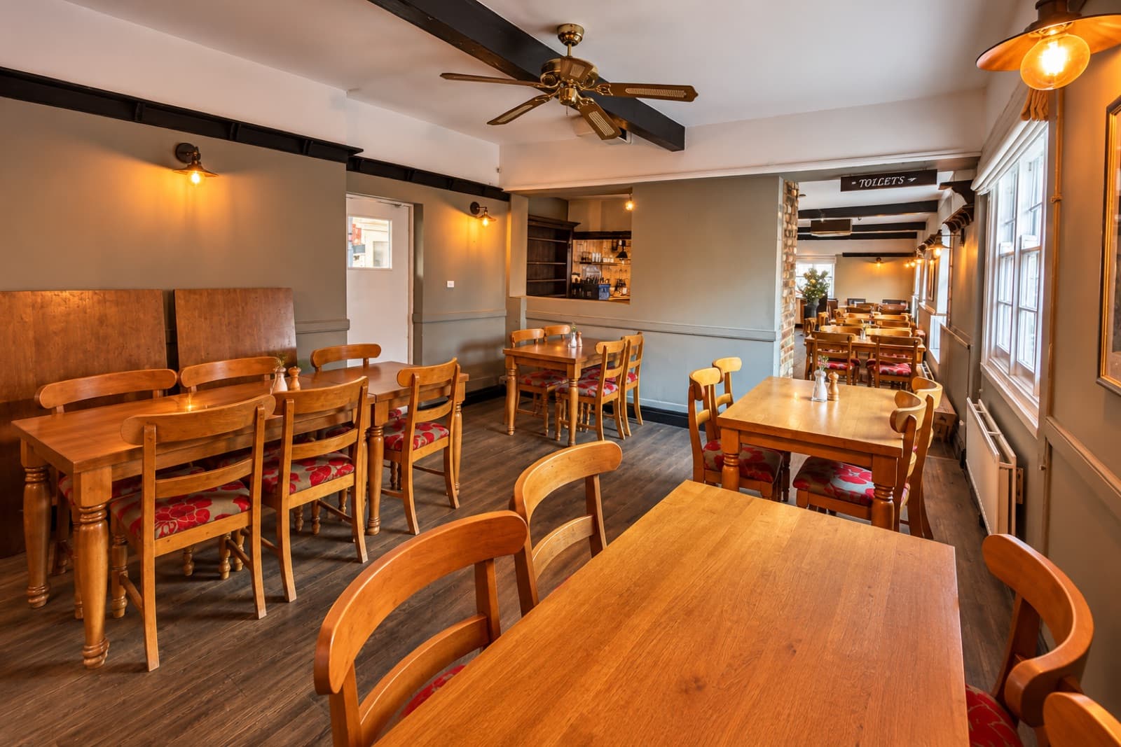 Wooden tables, grey panelling and connected rooms beside the windows at The White Horse Inn in Swavesey.
