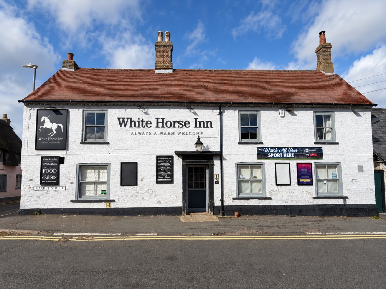 Front view of The White Horse Inn in Swavesey, with its pub sign, white brickwork and Market Street entrance.