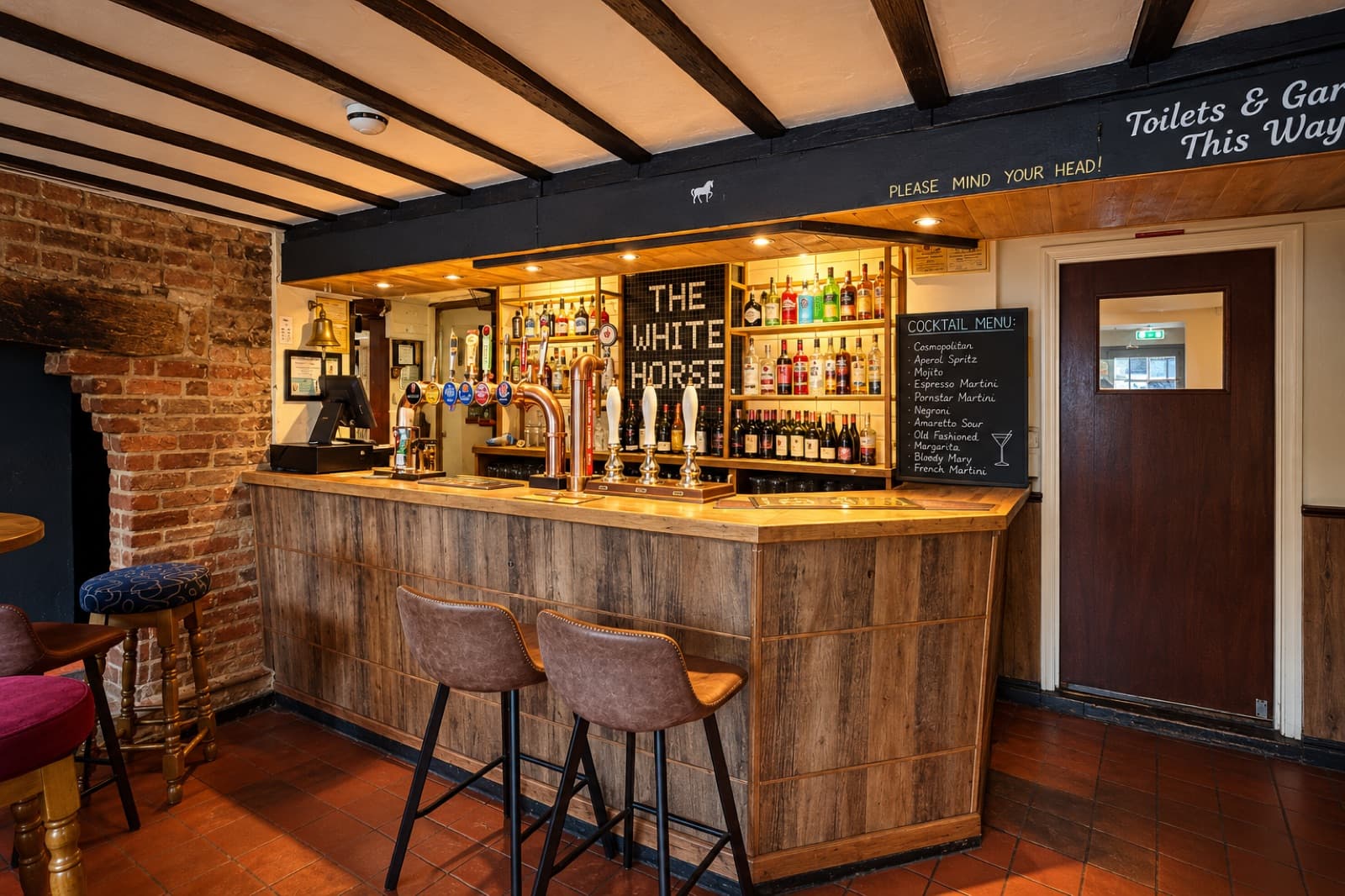 Timber bar, brass beer pumps, exposed brick and black beams at The White Horse Inn in Swavesey.